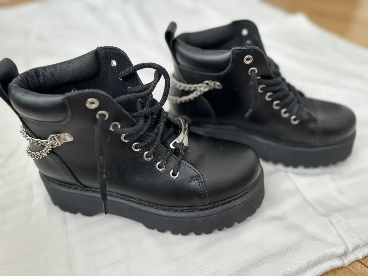 Borceguies negros de cuero con plataforma y detalles de cadenas plateadas. Estilo rocker y urbano, ideales para un look audaz.