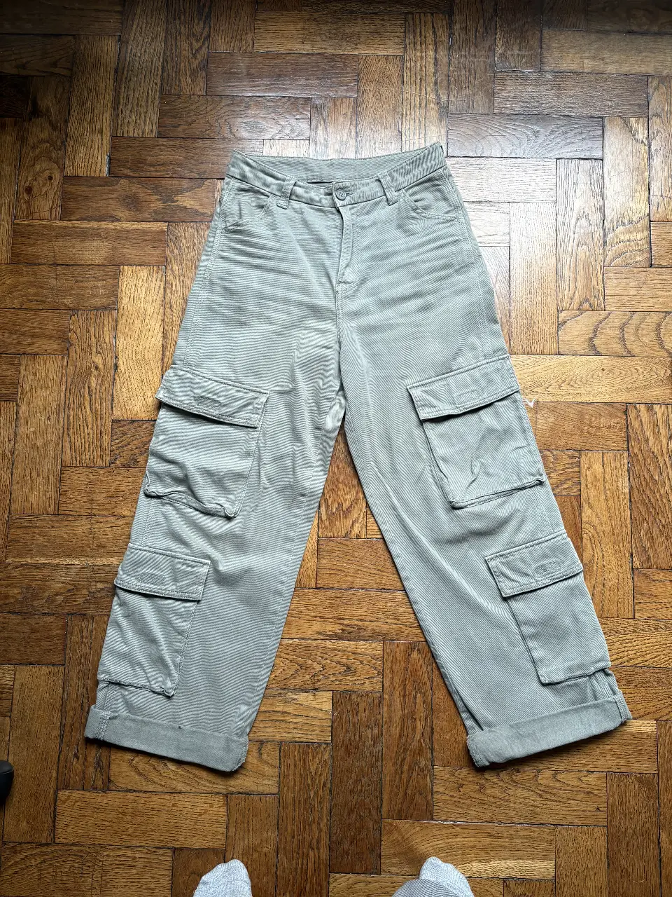 Pantalón cargo verde/ gris, tiro alto y corte ancho. Cuenta con múltiples bolsillos y un estilo utilitario. Ideal para un look casual y cómodo.