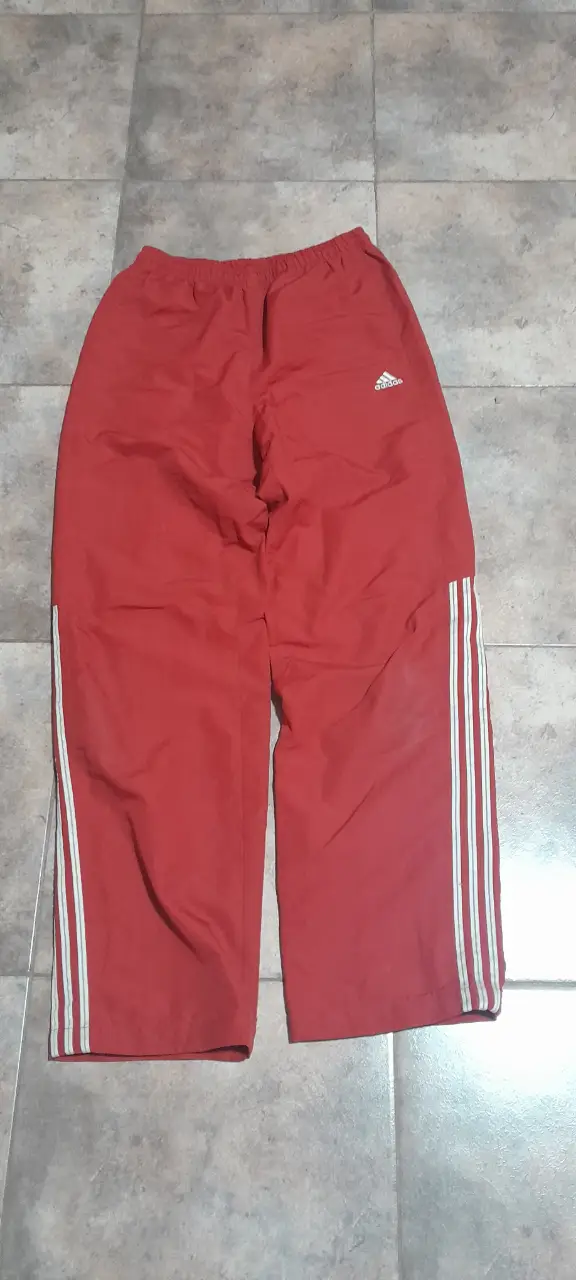 Pantalón deportivo Adidas rojo con las tres tiras blancas a los costados. Ideal para hacer deporte o para un look casual.