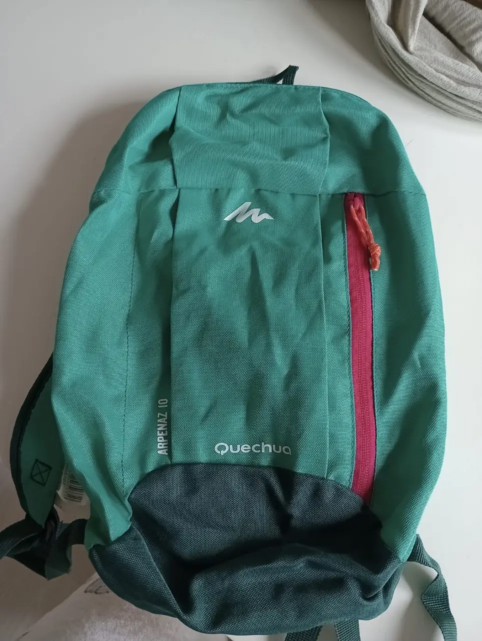 Mochila Quechua Arpenaz 10, ideal para actividades al aire libre. Color verde con detalles en rosa. Perfecta para llevar tus esenciales.