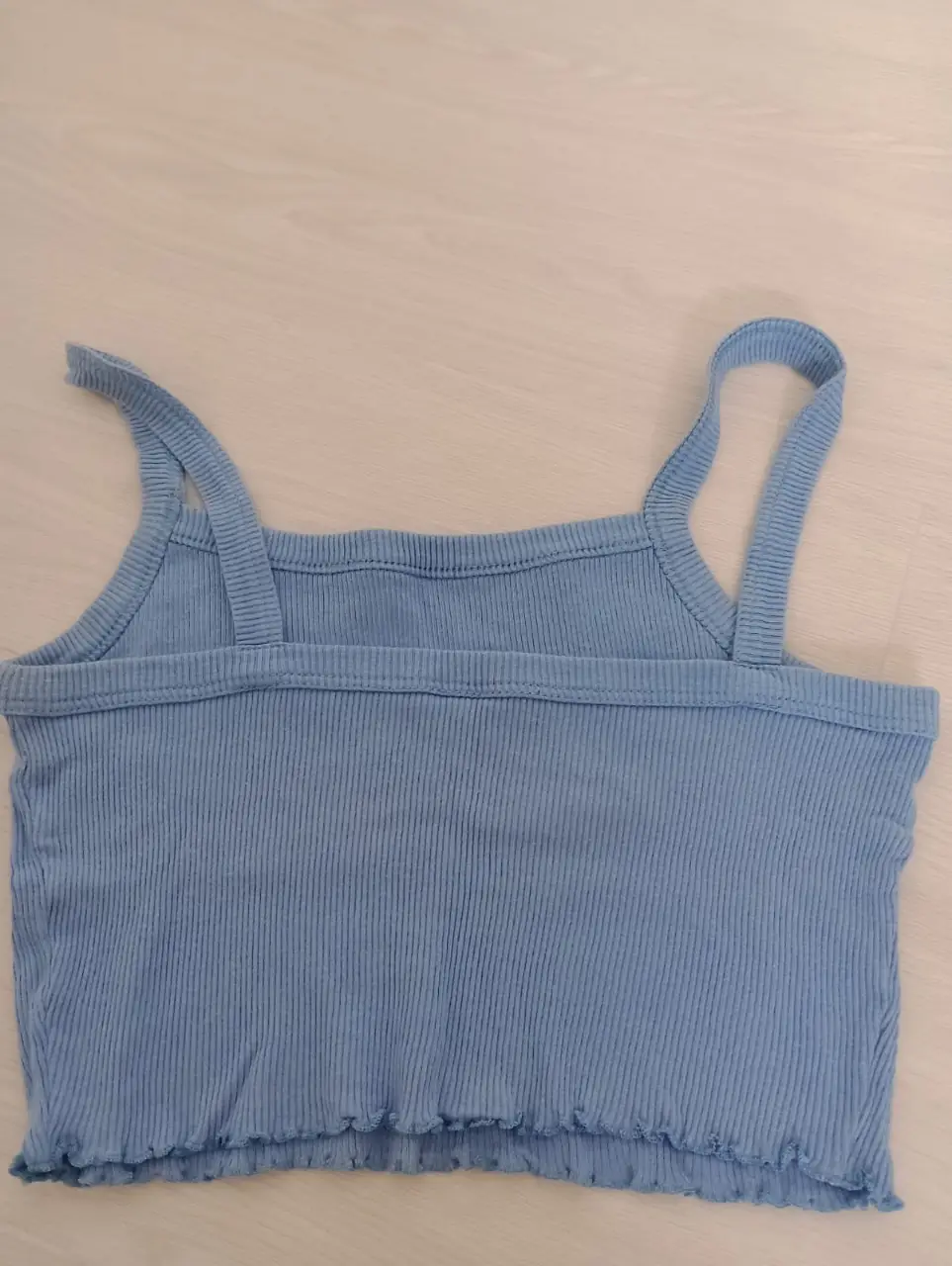 Top musculosa de mujer, color celeste, con breteles finos y detalle de volado en el borde inferior. Ideal para el verano.