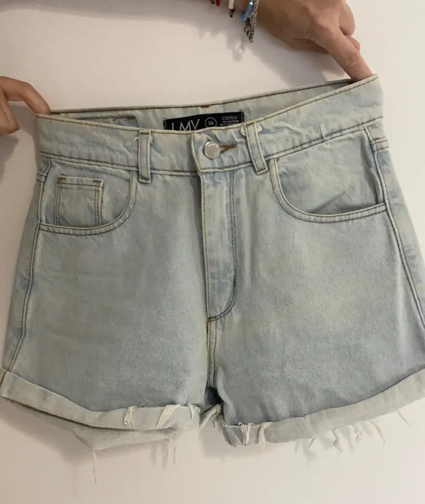 Short de jean celeste de mujer, tiro alto, con dobladillo en el borde inferior. Ideal para un look casual y fresco.