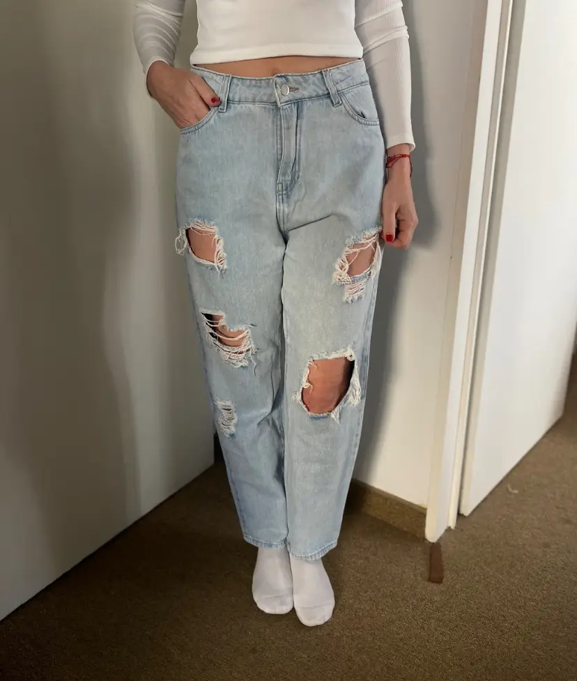 Jeans de mujer celeste claro con roturas en las rodillas. Tiro alto, corte recto y estilo oversize. Ideal para un look casual y moderno.