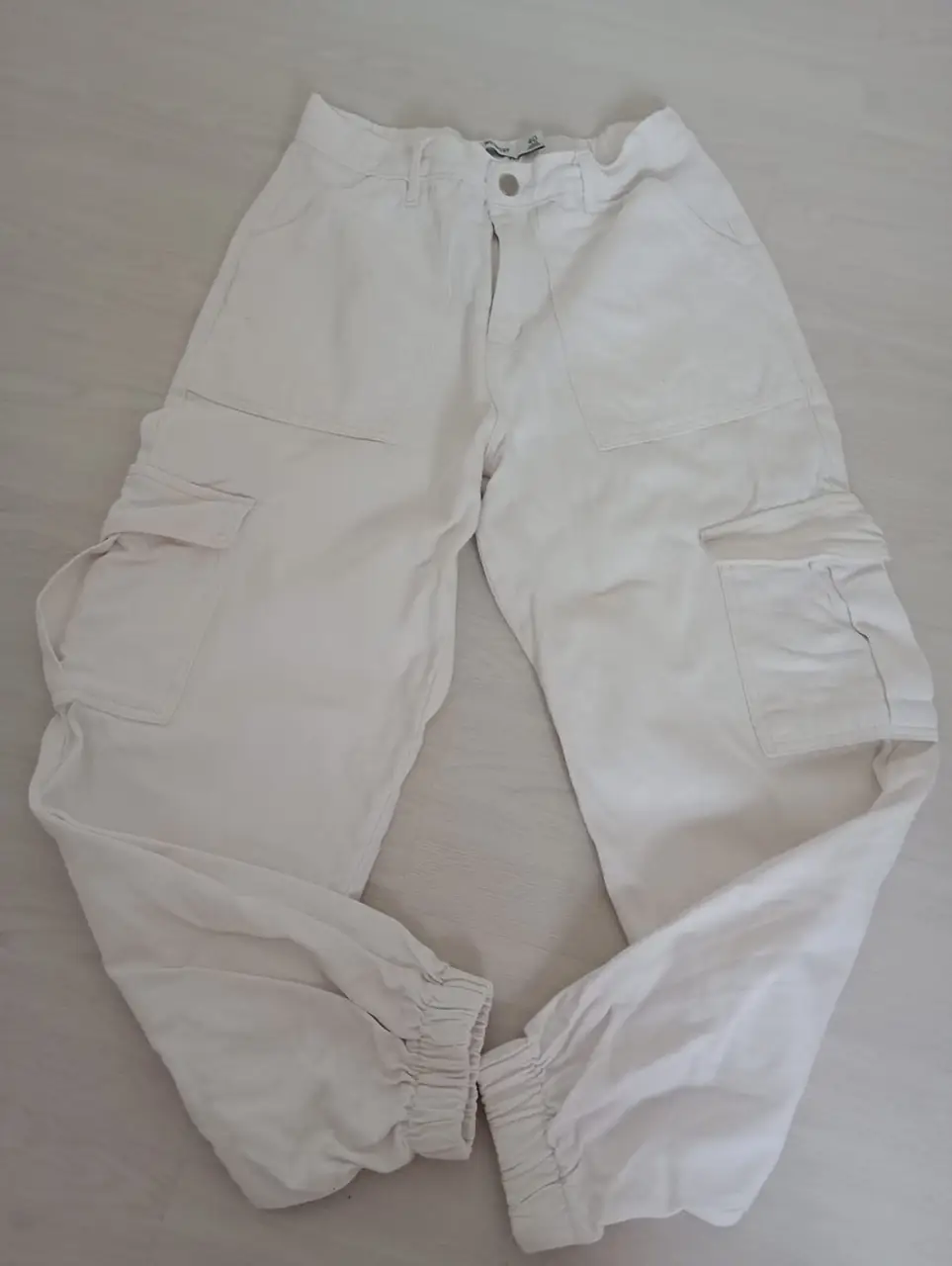 Pantalón cargo blanco, tiro medio, con bolsillos laterales y en la parte trasera. Ideal para un look casual y moderno.