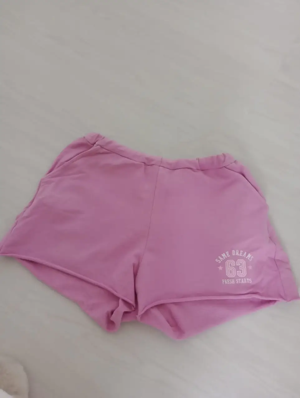 Short deportivo de color rosa con estampado "SAME DREAMS 63 FRESH STARTS". Ideal para actividades deportivas o para un look casual y cómodo.