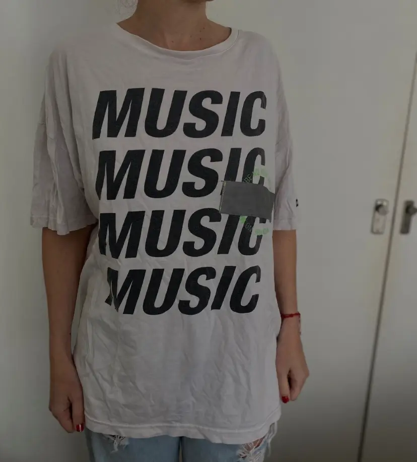 Remera oversize MARCA BUDDIES  de algodón con estampado "MUSIC" en negro. Ideal para un look casual y urbano. Perfecta para combinar con jeans o shorts.