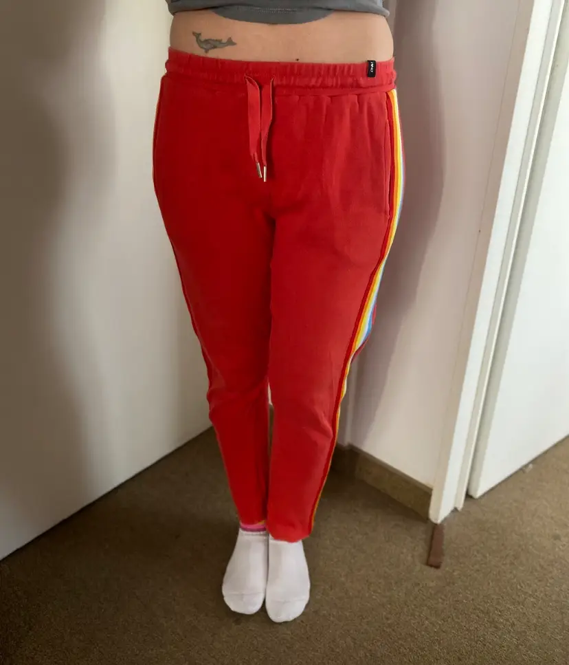Pantalón deportivo rojo con franjas laterales multicolores. Ideal para un look casual y cómodo.