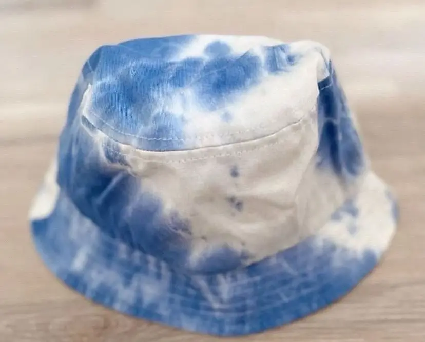 Piluso de tela con diseño tie dye en tonos azules y blancos. Ideal para un look casual y moderno.