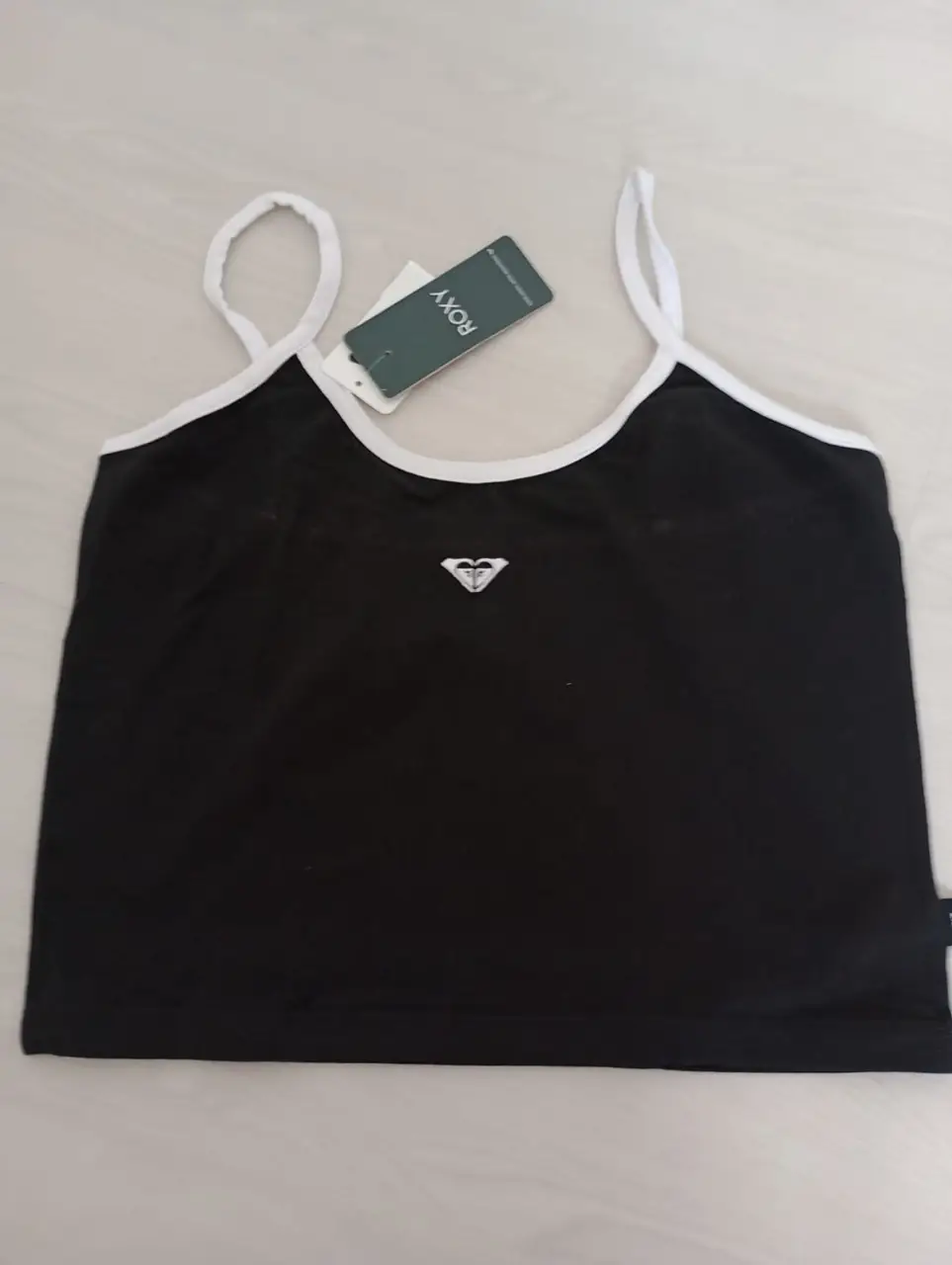 Top negro con detalles blancos y logo de la marca Roxy. Ideal para un look casual y cómodo.