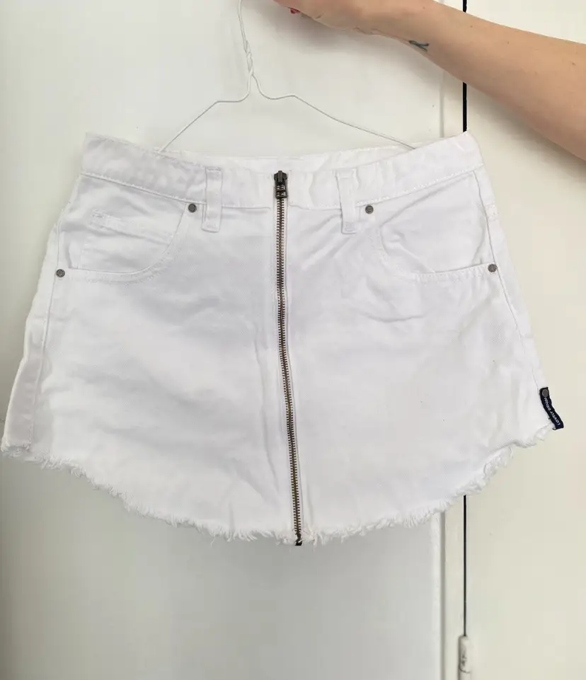Short de jean blanco con cierre frontal y corte desflecado. Talle 28, ideal para un look casual y moderno.
