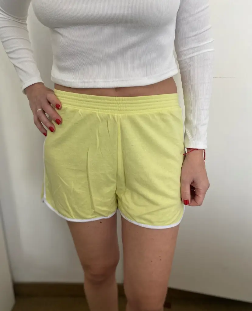 Short deportivo de mujer, color amarillo pastel con detalles blancos. Talle M. Ideal para actividades deportivas o uso casual.