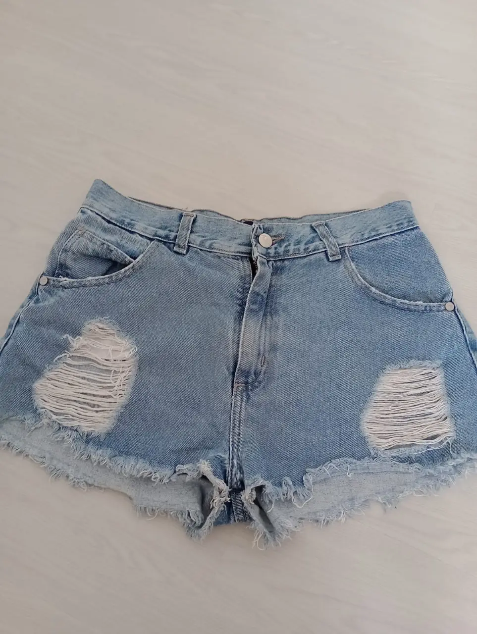 Short de jean de mujer, tiro medio, con roturas en las piernas. Ideal para un look casual y moderno.
