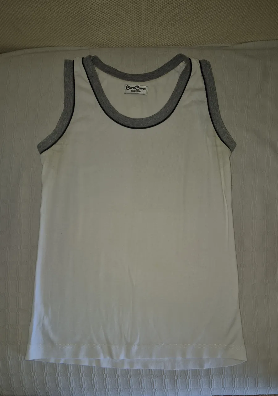 Musculosa blanca con detalles grises en cuello y mangas. Ideal para el día a día o para usar como prenda deportiva.