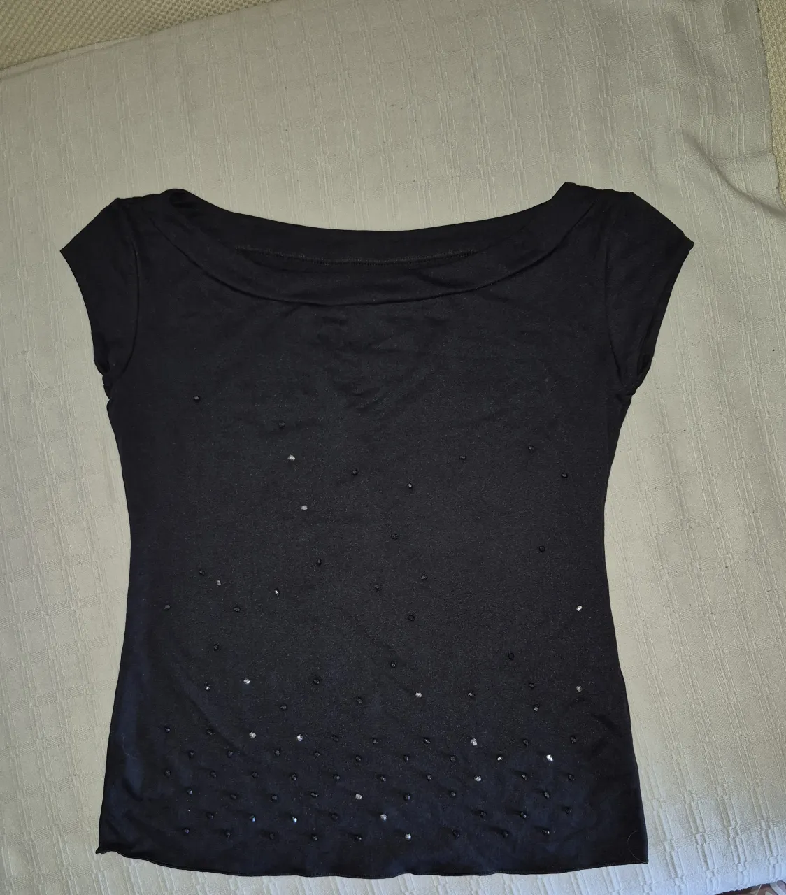 Remera negra con cuello barco y detalles de brillos sutiles. Manga corta, ideal para un look canchero y elegante.
