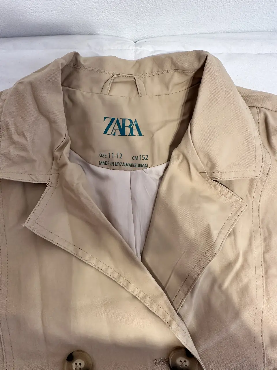Trench coat de la marca Zara, color crudo, con cinturón y botones. Ideal para un look elegante y versátil. kids 13/14