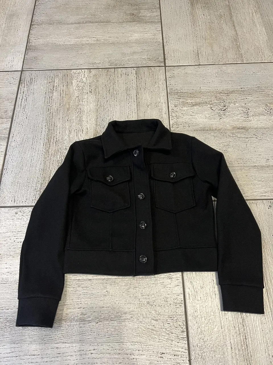 Camisaco, tapado cort negro, con botones y bolsillos delanteros. Ideal para un look casual y moderno. talle único.