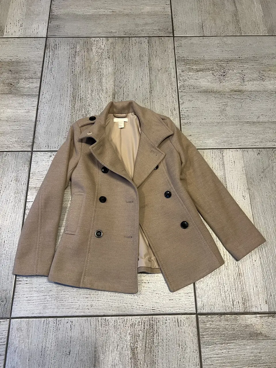 Abrigo tipo tapado corto de paño color marrón claro, con botones negros y solapas. Ideal para un look elegante y abrigado.