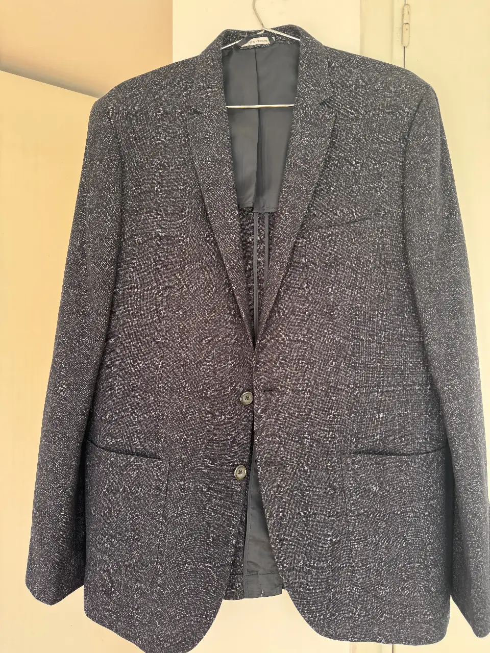 Elegante blazer de hombre en tonos azul y gris, ideal para un look formal o de trabajo. Confeccionado con un tejido texturizado de alta calidad, este blazer ofrece un ajuste slim fit y detalles cuidados como botones en las mangas y bolsillos funcionales. Perfecto para combinar con pantalones de vestir o jeans.