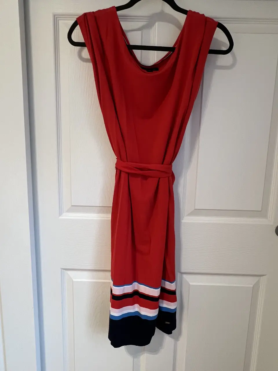 Vestido midi rojo con cinturón a juego. Detalles en blanco, negro y azul en el bajo. Ideal para un look casual y fresco.
