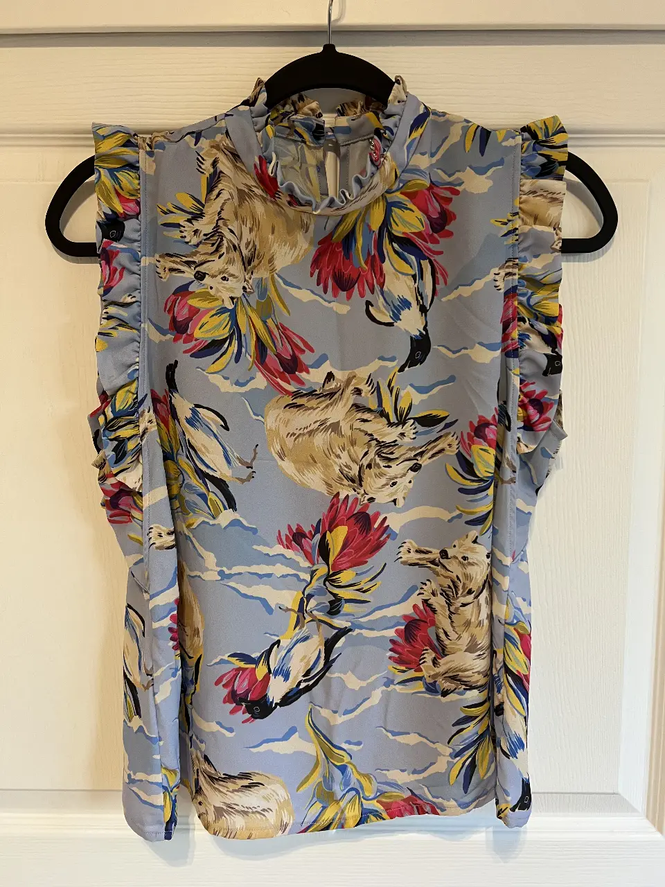 Blusa de mujer con estampado floral y cuello alto. Diseño con volados en las mangas y cierre en la parte trasera. Ideal para un look elegante y fresco.