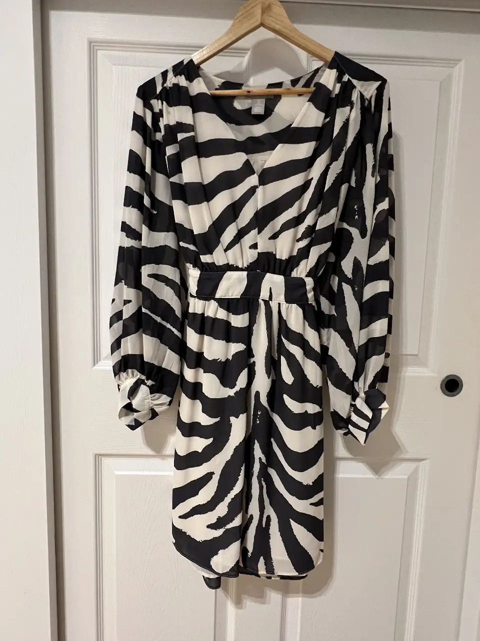 Vestido midi con estampado de cebra en blanco y negro. Tiene mangas largas con puños y cintura entallada. Marca H&M.
