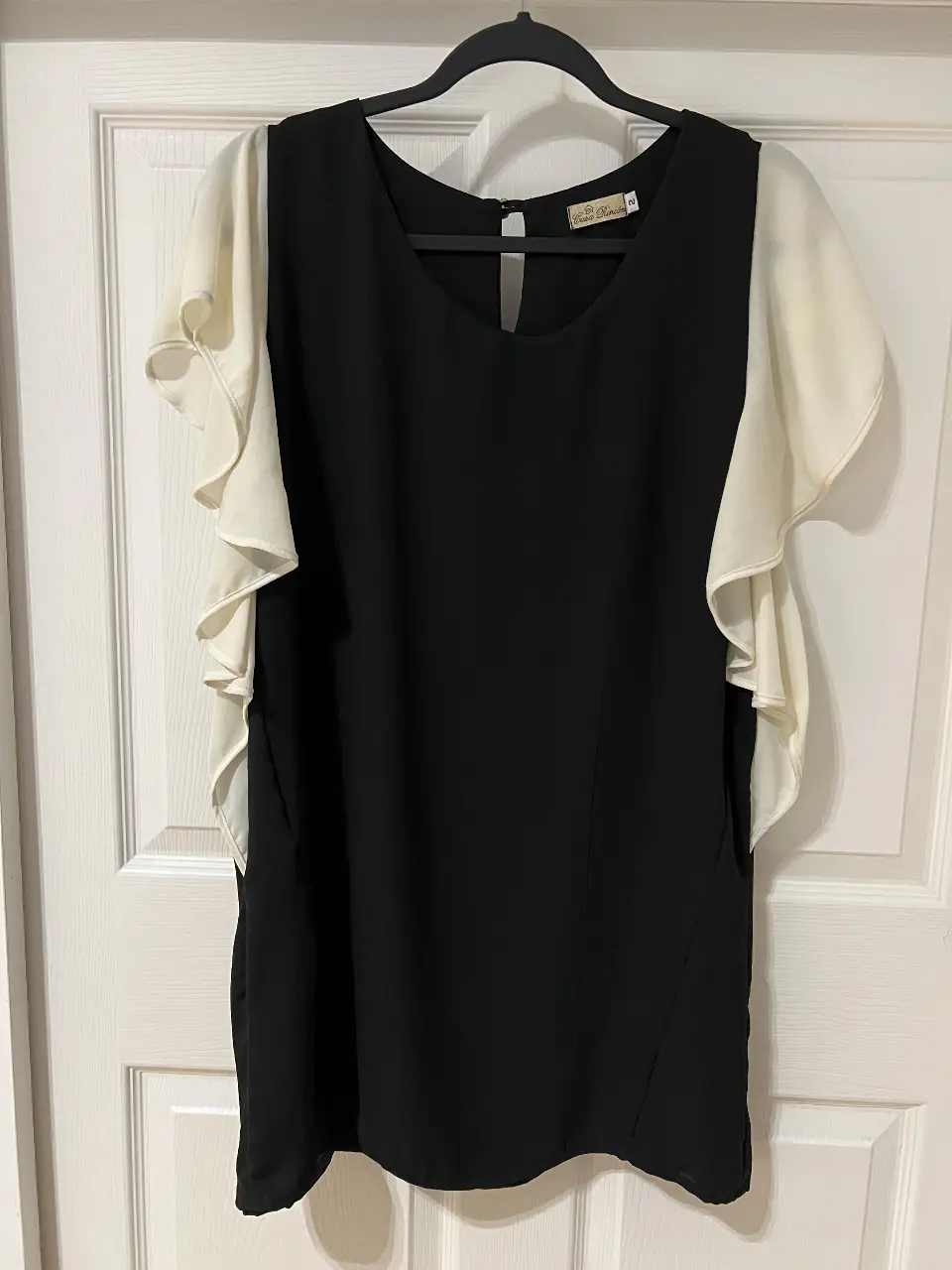 Blusa de mujer con mangas con volados en color blanco y cuerpo negro. Ideal para un look elegante y sofisticado.
