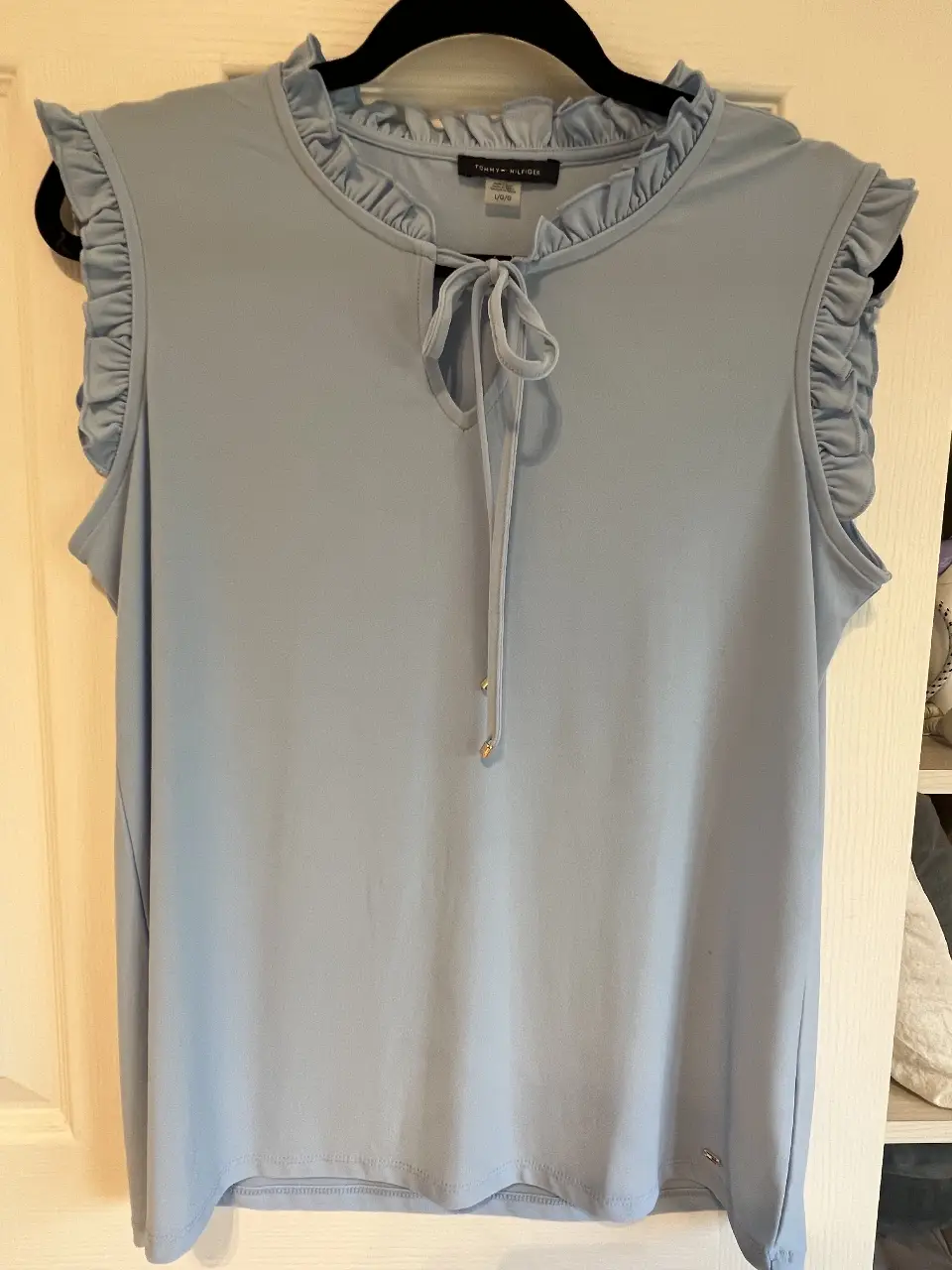 Blusa celeste de Tommy Hilfiger, con cuello redondo y detalle de lazo. Tiene volados en las mangas y es ideal para un look casual y elegante.