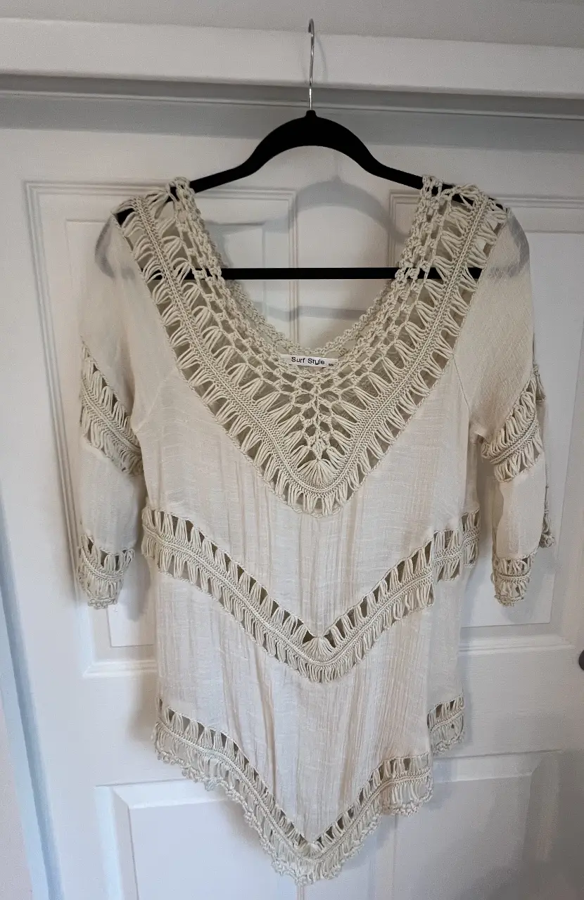 Blusa de estilo boho en color crudo, con detalles artesanales de crochet en el cuello y mangas. Ideal para un look fresco y relajado.