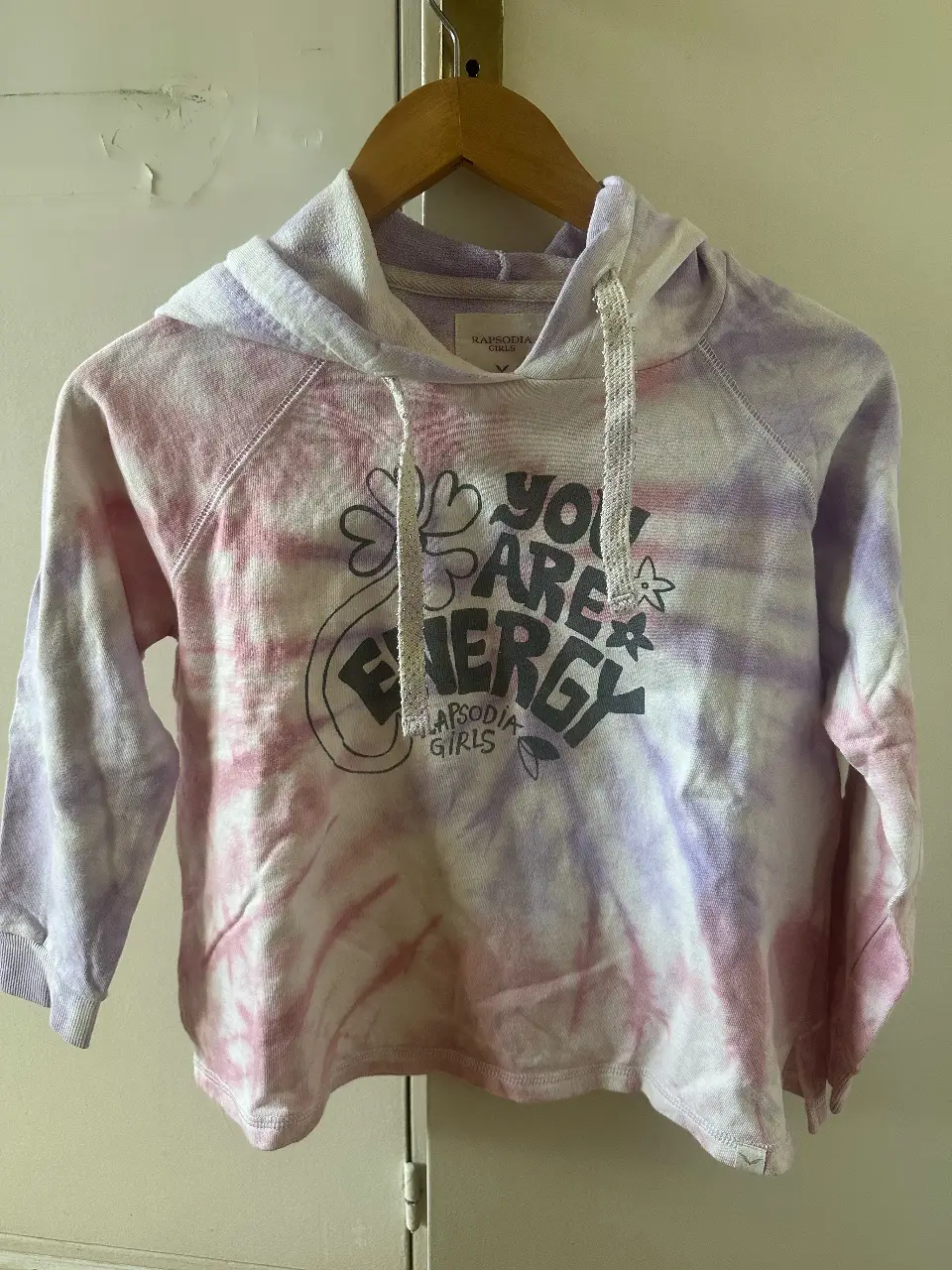Buzo canguro para niña con diseño tie dye en tonos rosa y violeta. Estampado "You are energy" en el frente. Ideal para un look casual y cómodo.