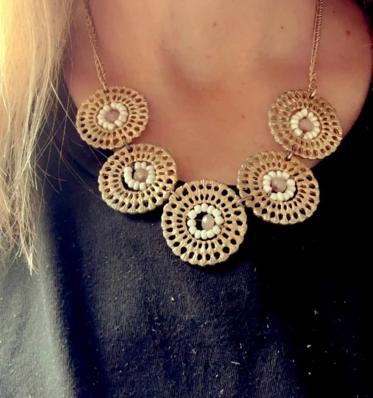 Collar dorado con dijes circulares calados y detalles de cuentas blancas. Un accesorio elegante y llamativo para complementar cualquier look.