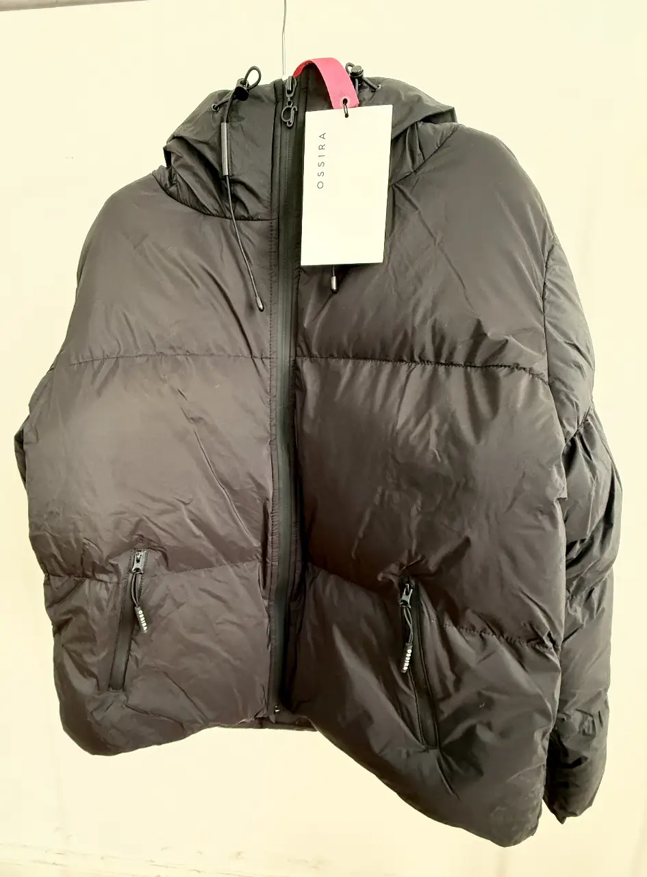 Campera de pluma negra, ideal para el invierno. Con capucha y cierre frontal y Bolsillos con cierre sellado y etiqueta de la marca OSSIRA.