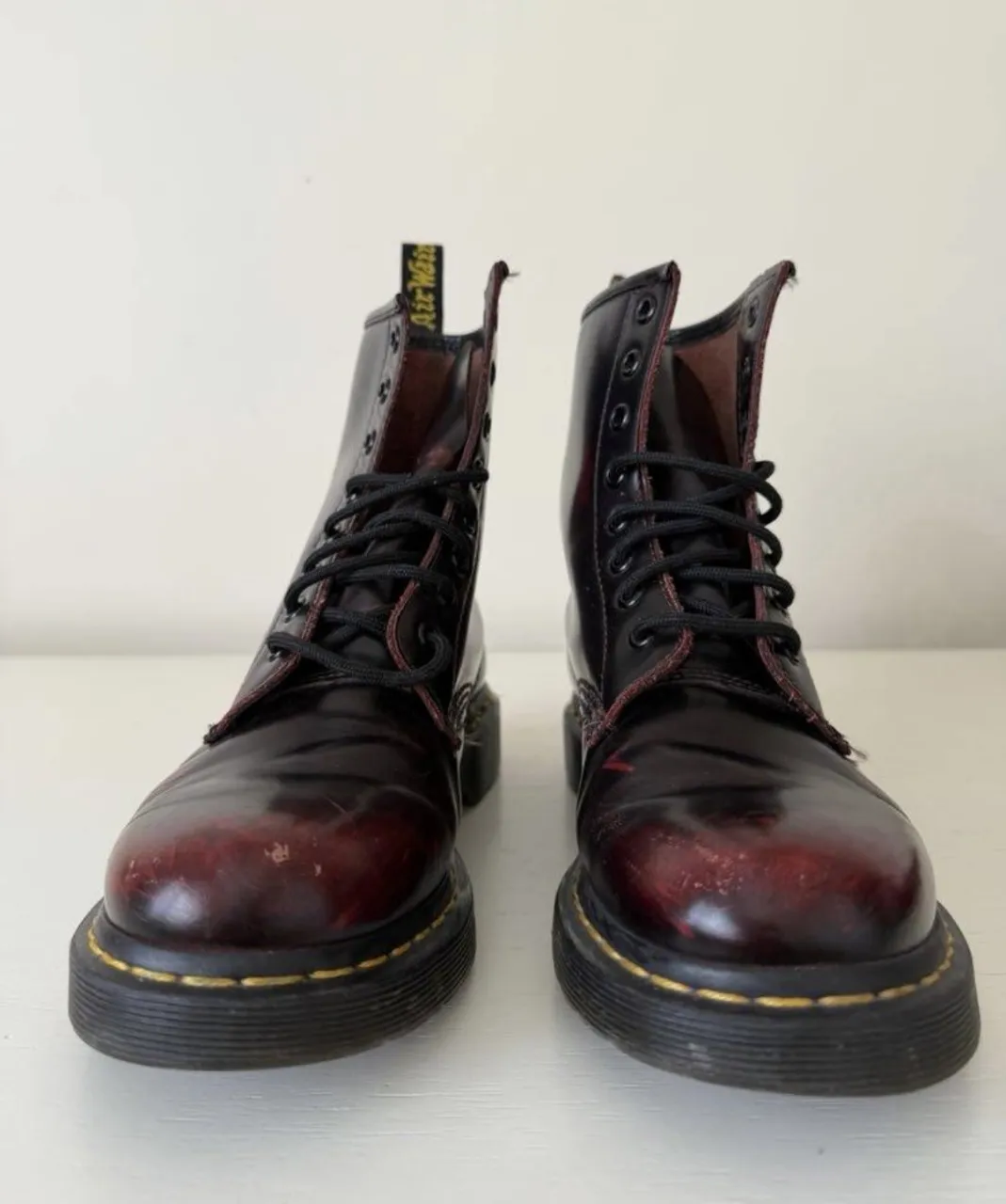 Botas de cuero color bordó con desgastes, cordones negros y suela negra con costuras amarillas.