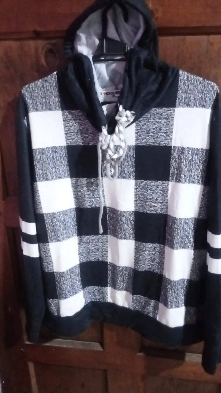 Buzo canguro con capucha a cuadros blanco y negro. Ideal para un look casual y canchero. Confeccionado en tela suave y cómoda, perfecto para el día a día.