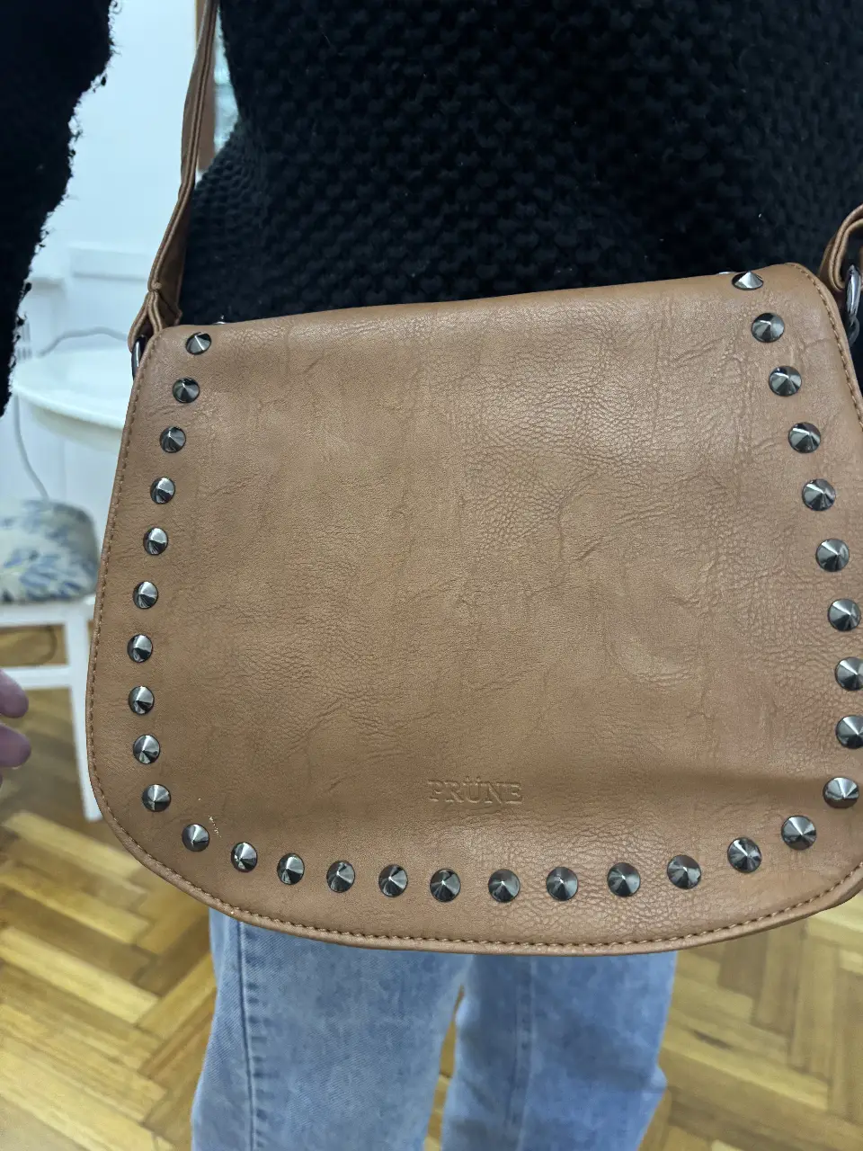 Bandolera marrón con tachas de la marca Prune. Ideal para un look casual y canchero. Cuenta con correa ajustable y cierre.