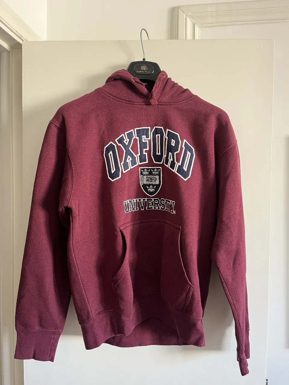Buzo canguro de la Universidad de Oxford para mujer. Color borgoña con estampado en blanco. Ideal para un look casual y cómodo.