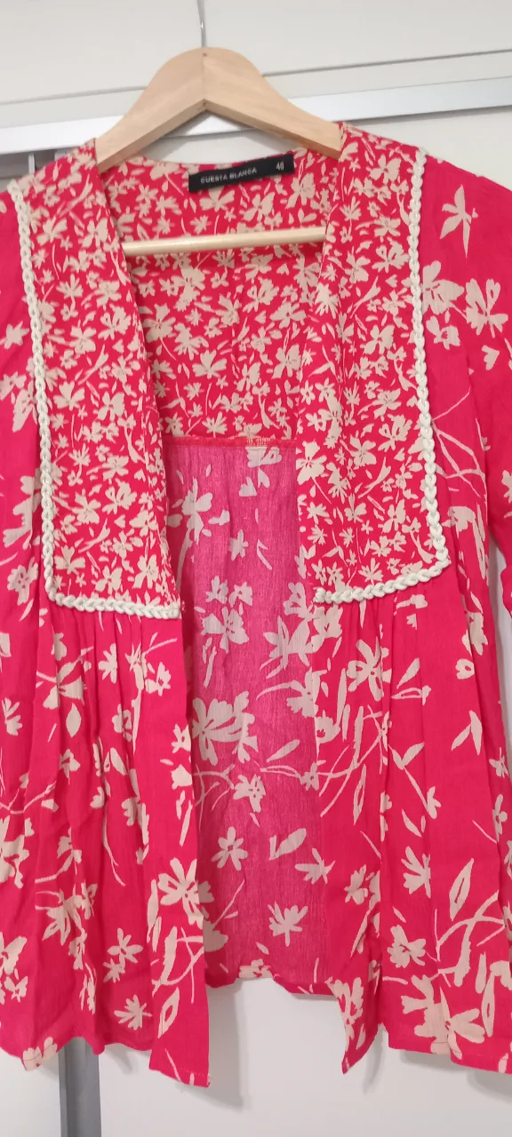 Blusa o torera estampada con flores en fucsia y detalles en blanco. Posee un diseño delicado con terminaciones en puntilla y un escote cuadrado. Ideal para un look fresco y femenino.