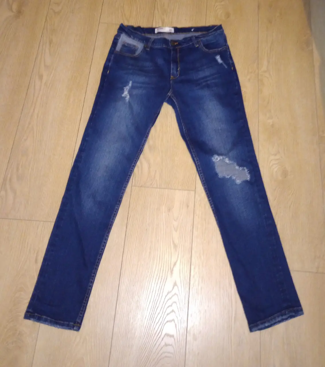 Jeans rectos de mujer, azul oscuro con roturas en las rodillas. Un clásico para cualquier ocasión.