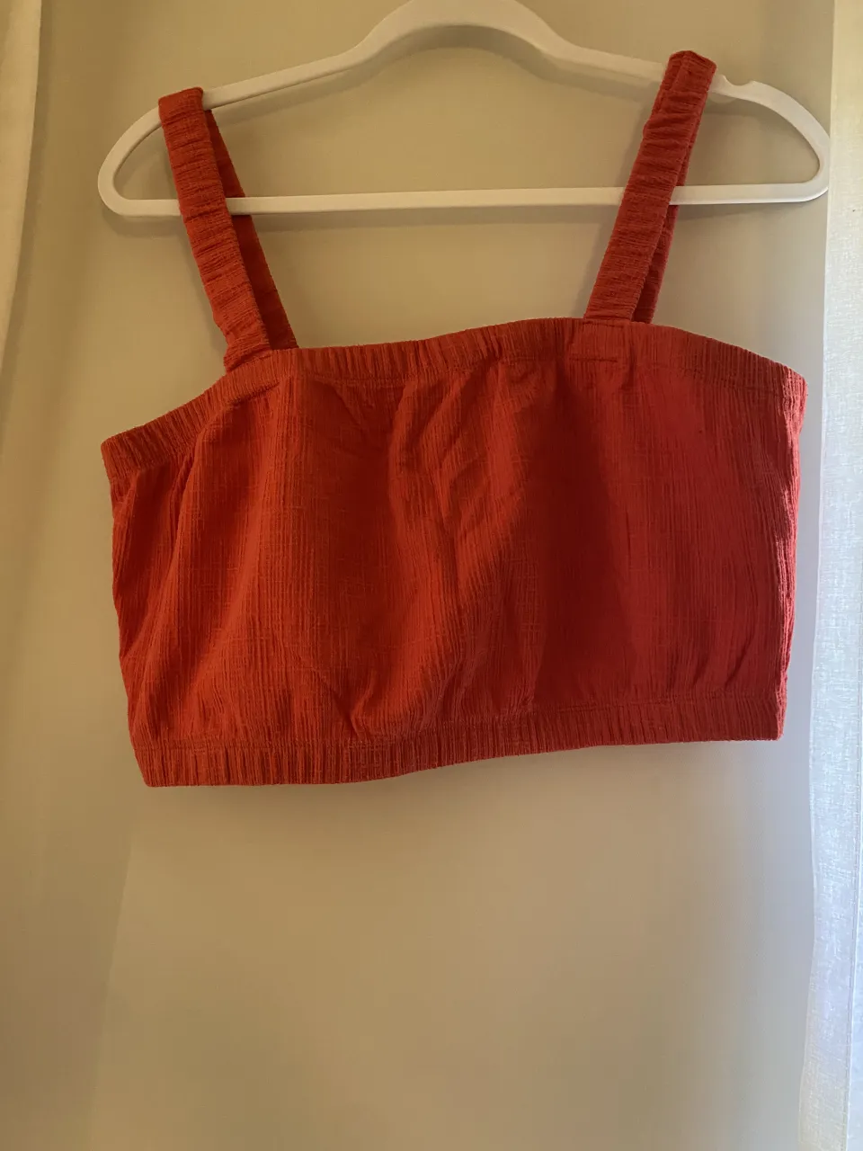 Top naranja de breteles anchos, ideal para el verano. Su textura le da un toque especial y es perfecto para combinar con shorts o faldas.