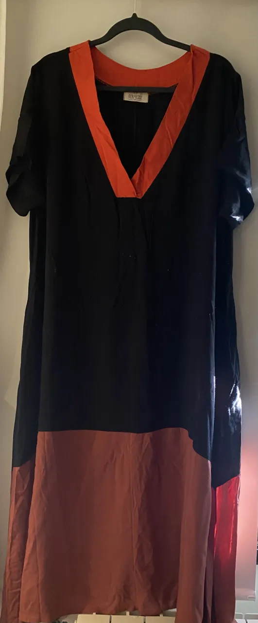 Vestido negro con detalles en naranja y terracota. Diseño moderno y cómodo, ideal para un look casual y chic. Perfecto para el día o una salida informal.