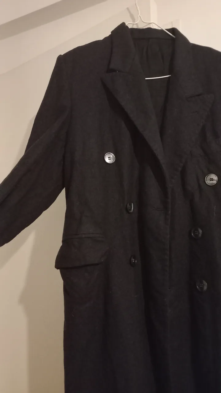 Sobretodo largo de paño negro, con corte de blazer, doble botonadura y bolsillos. Ideal para un look elegante y abrigado.