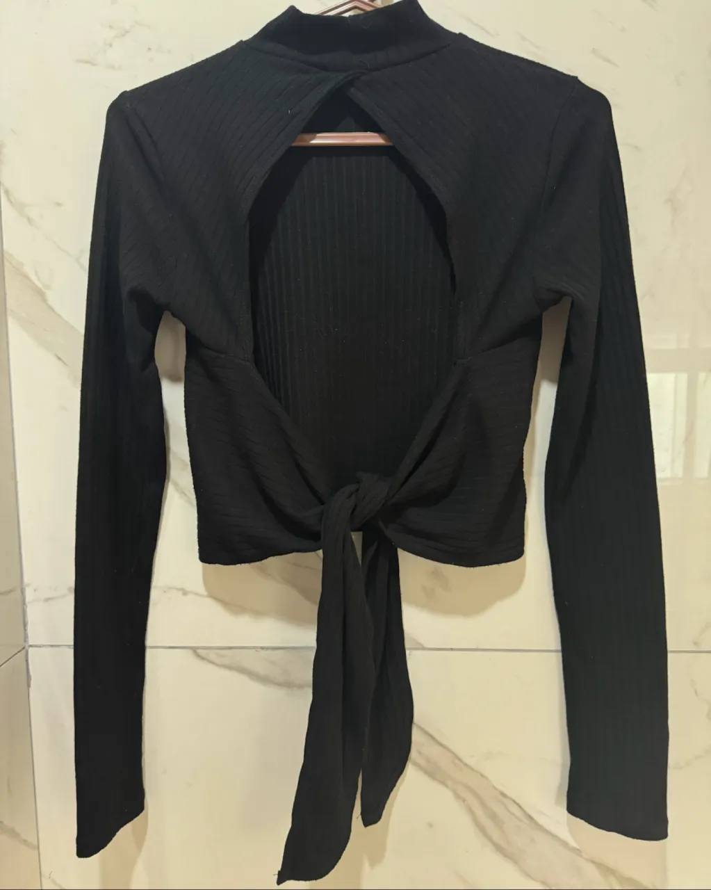 Remera negra de manga larga con cuello alto y lazo en la espalda. Posee un recorte en la espalda.