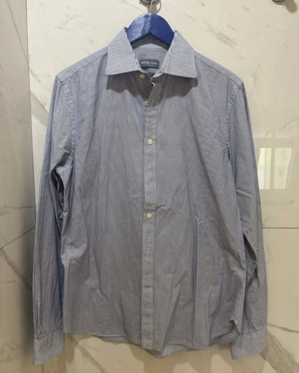 Camisa de vestir de manga larga con rayas finas en azul y blanco. Posee un corte slim fit, ideal para un look elegante y moderno. Perfecta para ocasiones formales o para el trabajo.