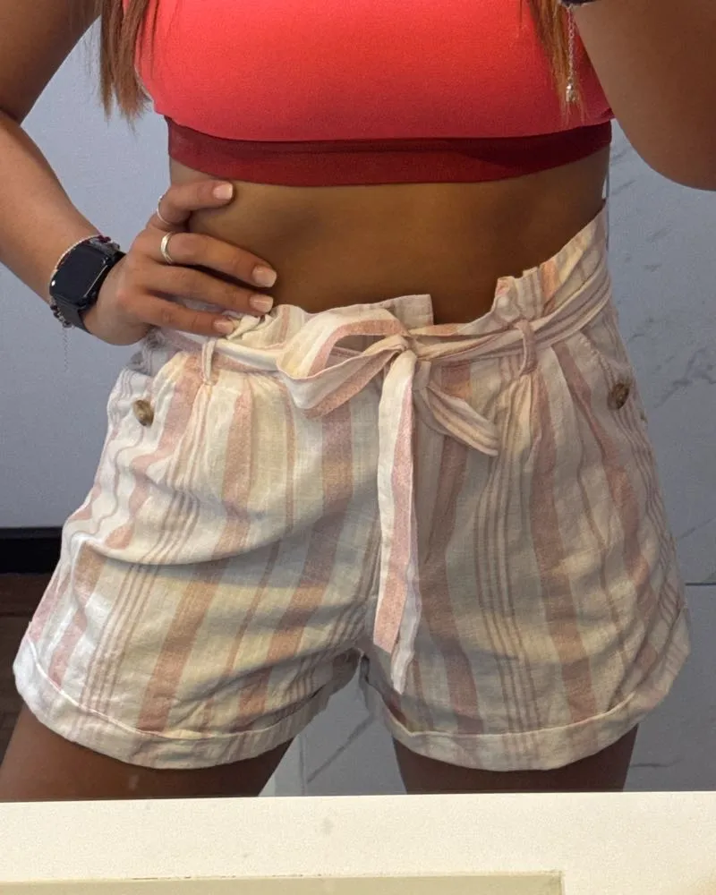 Shorts de lino a rayas blancas y rosas, tiro alto con lazo para anudar en la cintura. Ideales para un look fresco y casual de verano.