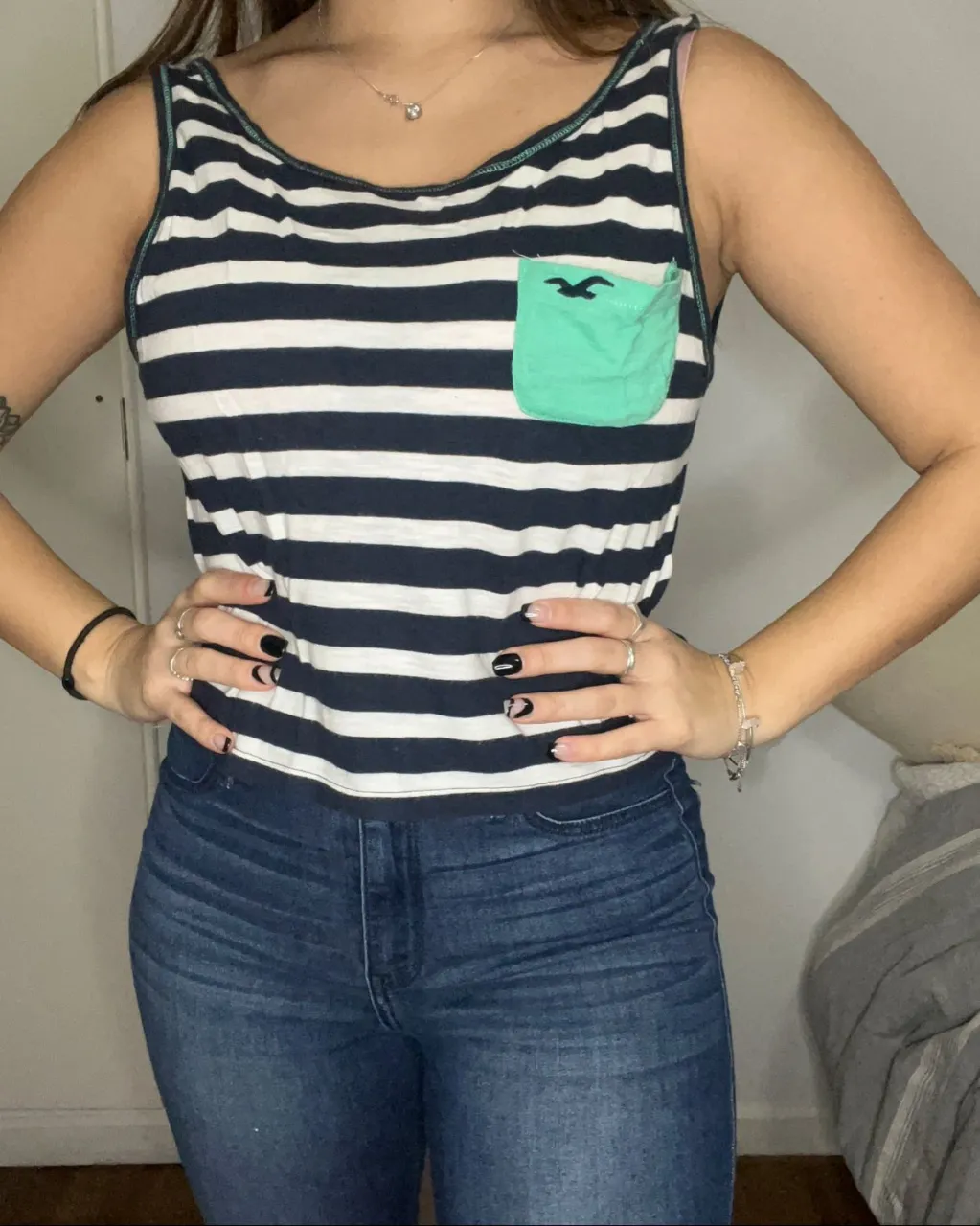 Musculosa a rayas azules y blancas con bolsillo verde en el frente.