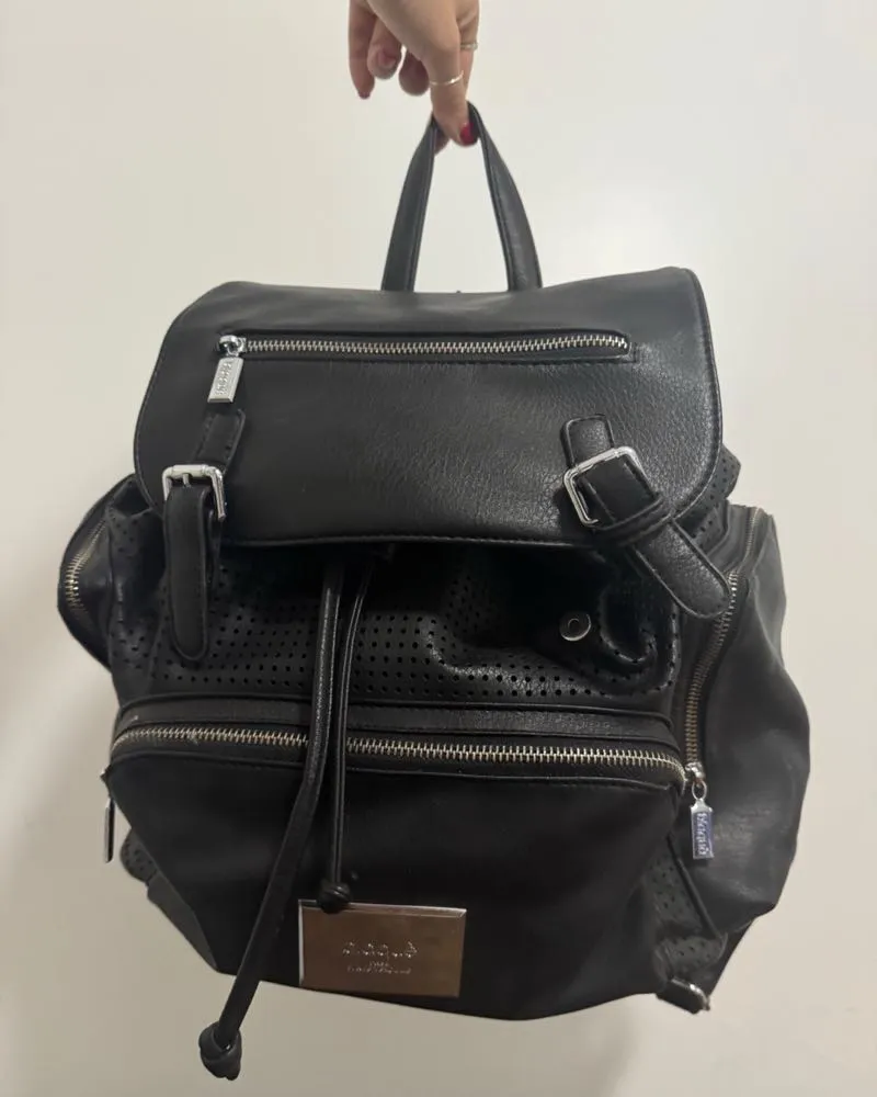 Mochila negra de cuero sintético, con múltiples bolsillos y detalles de perforaciones. Ideal para el día a día o para llevar tus esenciales a todos lados.