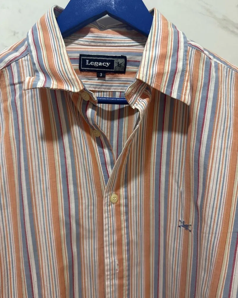 Camisa de manga larga a rayas verticales en tonos naranja, azul y blanco. Un clásico que nunca falla, ideal para un look casual o para ir a trabajar. Combina con todo y te da un estilo único.
