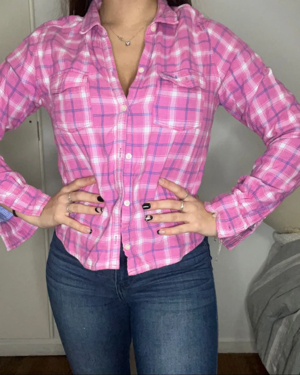 Camisa a cuadros de manga larga en tonos rosa y azul. Posee dos bolsillos en el frente y botones blancos.