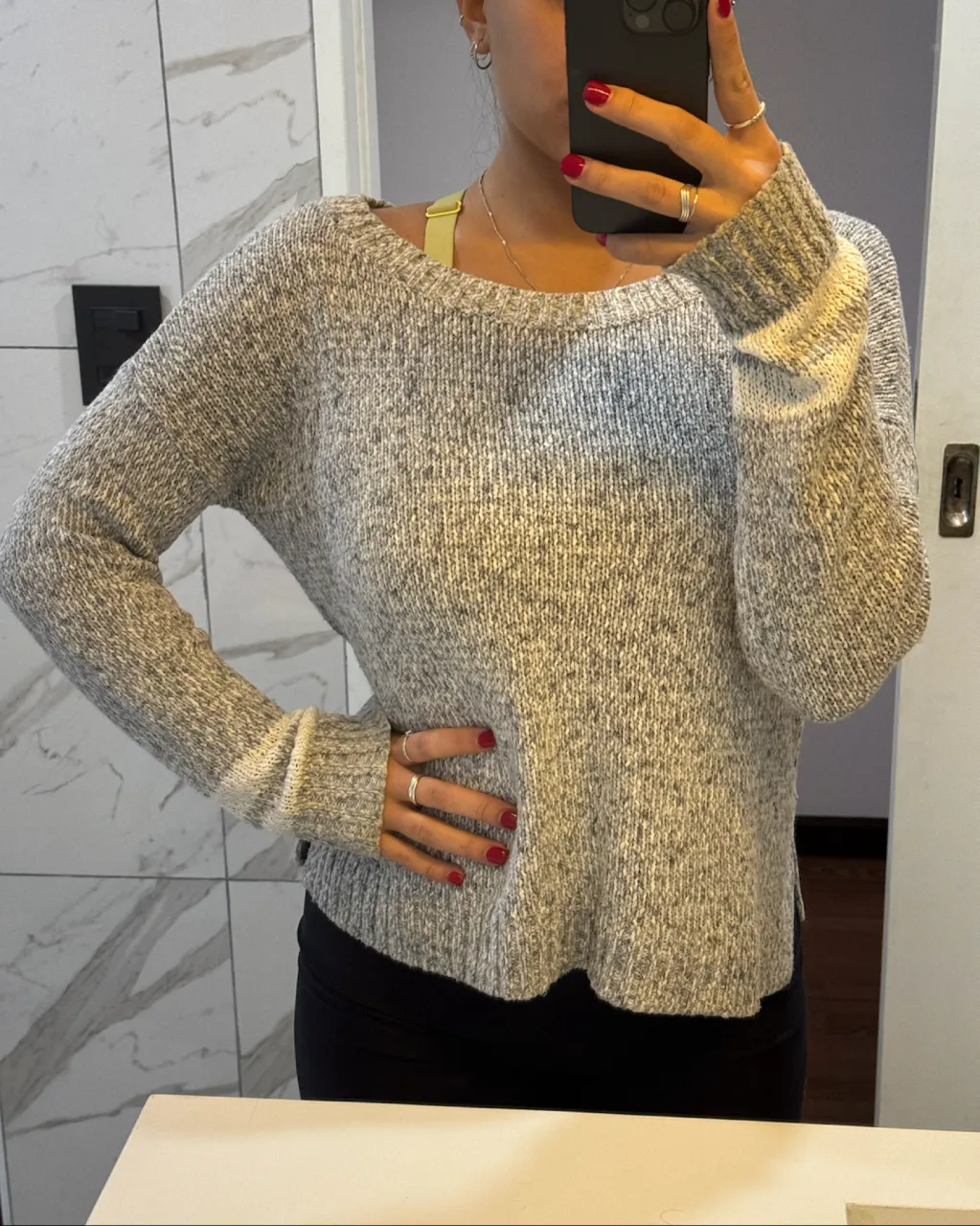Sweater tejido de manga larga con cuello redondo. Posee un diseño jaspeado en tonos de gris y blanco.