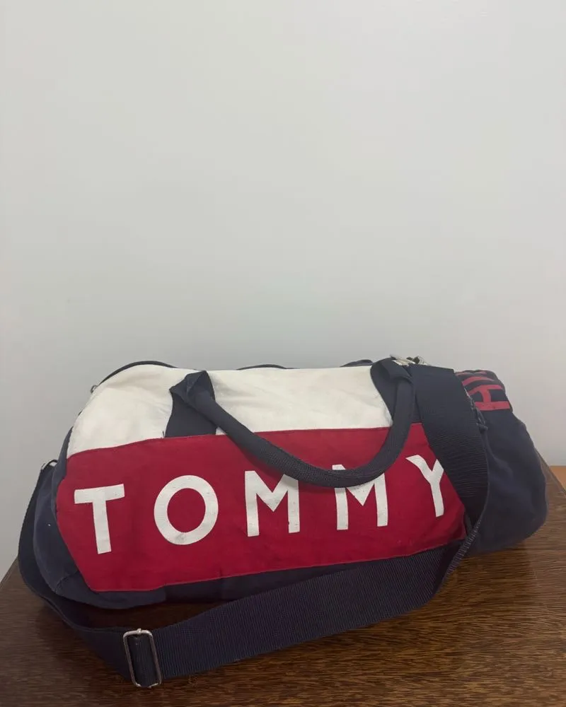 Bolsa de deporte "Tommy" original, ideal para viajes cortos o para llevar al gimnasio. Diseño clásico con los colores de la marca y logo grande al frente. Cuenta con manijas cortas y una correa larga regulable para llevar al hombro. Múltiples compartimentos para organizar tus pertenencias.