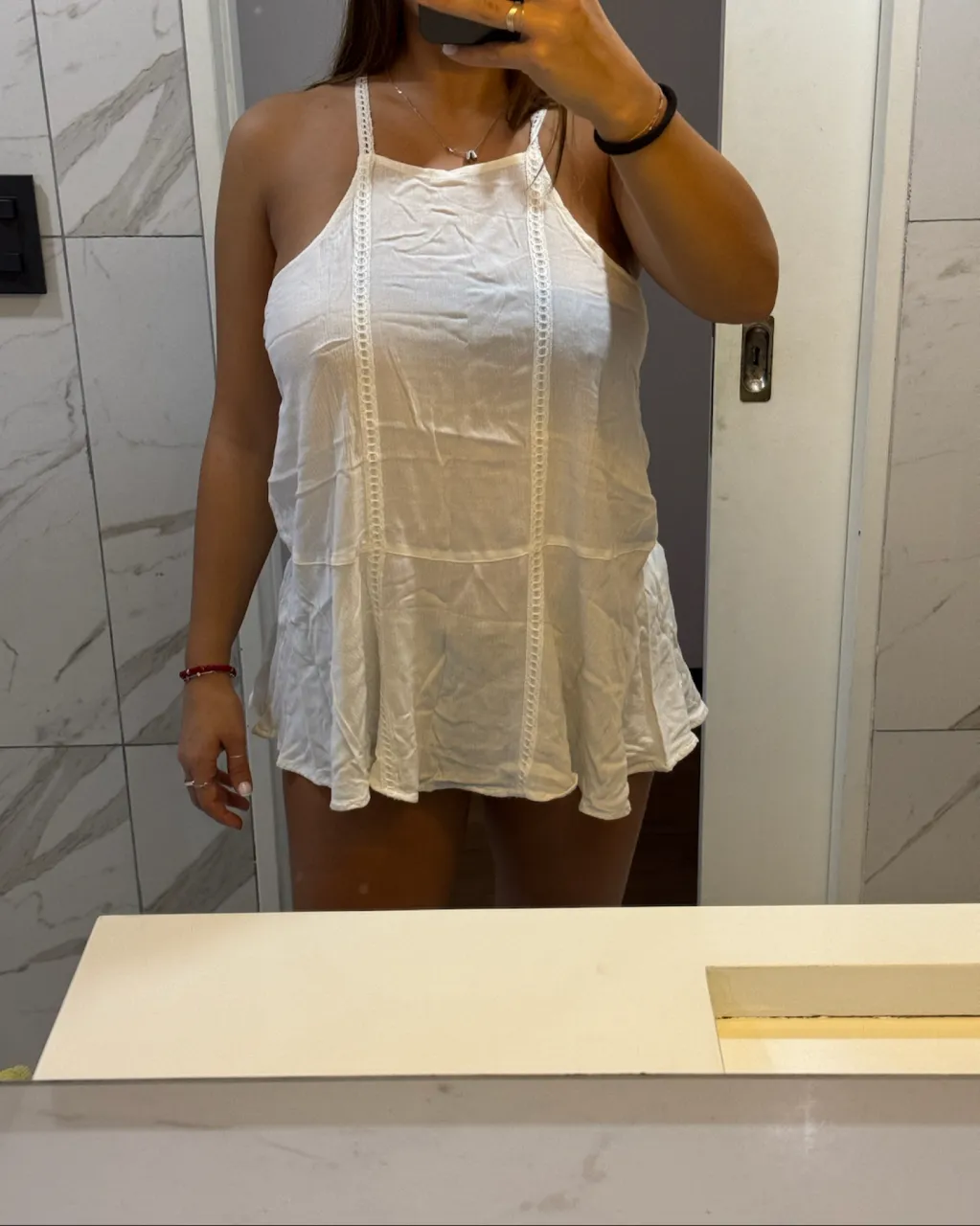 Musculosa blanca con detalles de puntilla en los breteles y en el frente. Largo hasta la cadera.